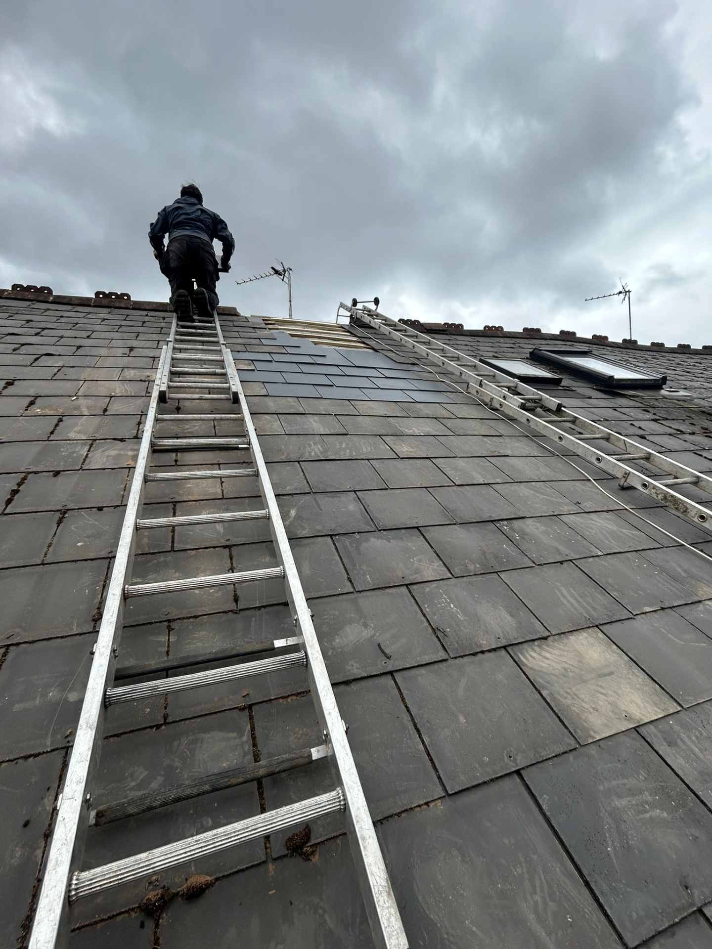 Roofer re-slating a pitched roof