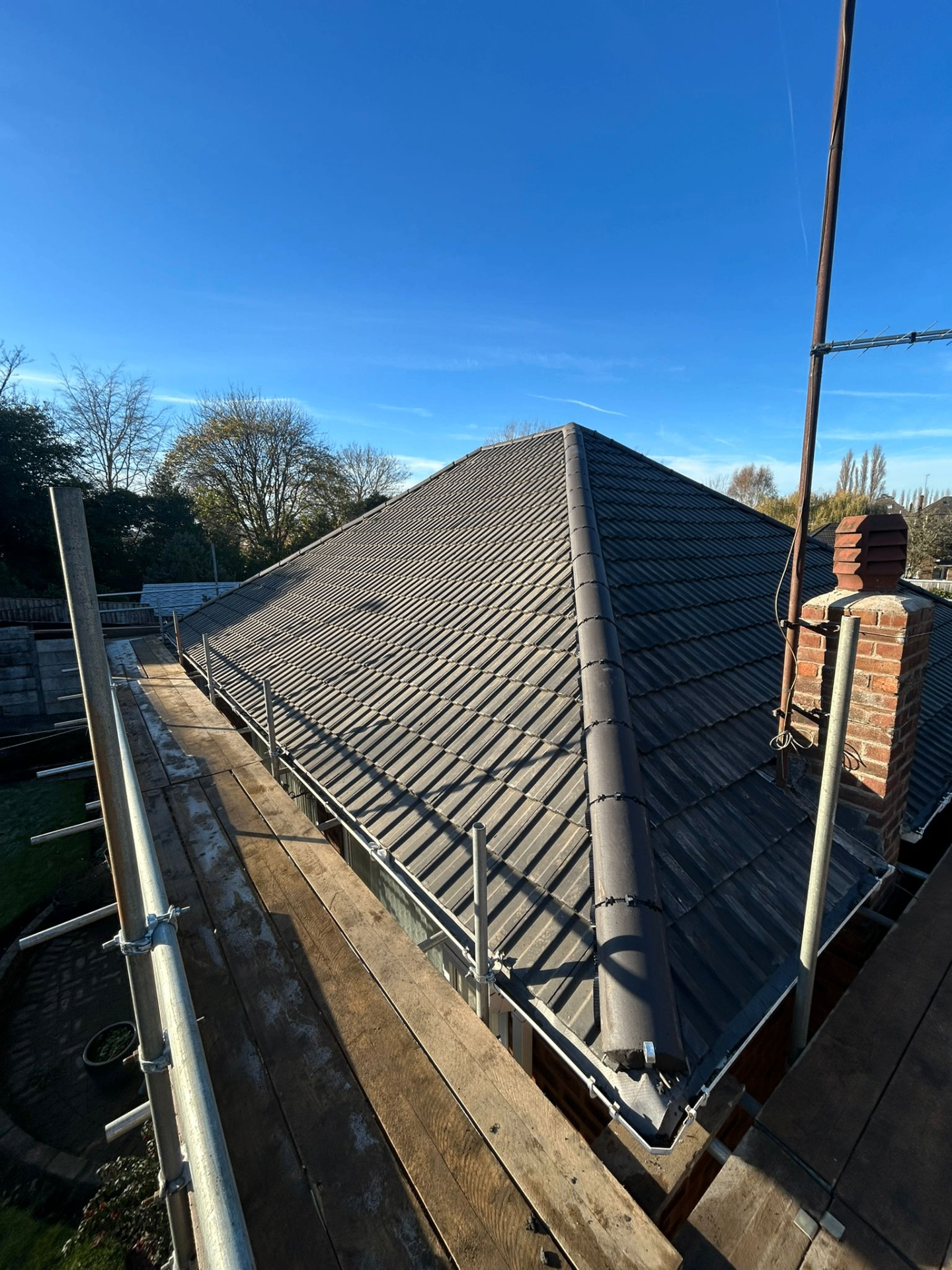 New grey tiled hipped roof with scaffolding